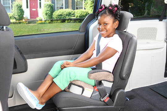 Smiling little girl seating on a car seat booster